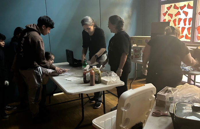 3 adults working the concession stand and families buying snacks